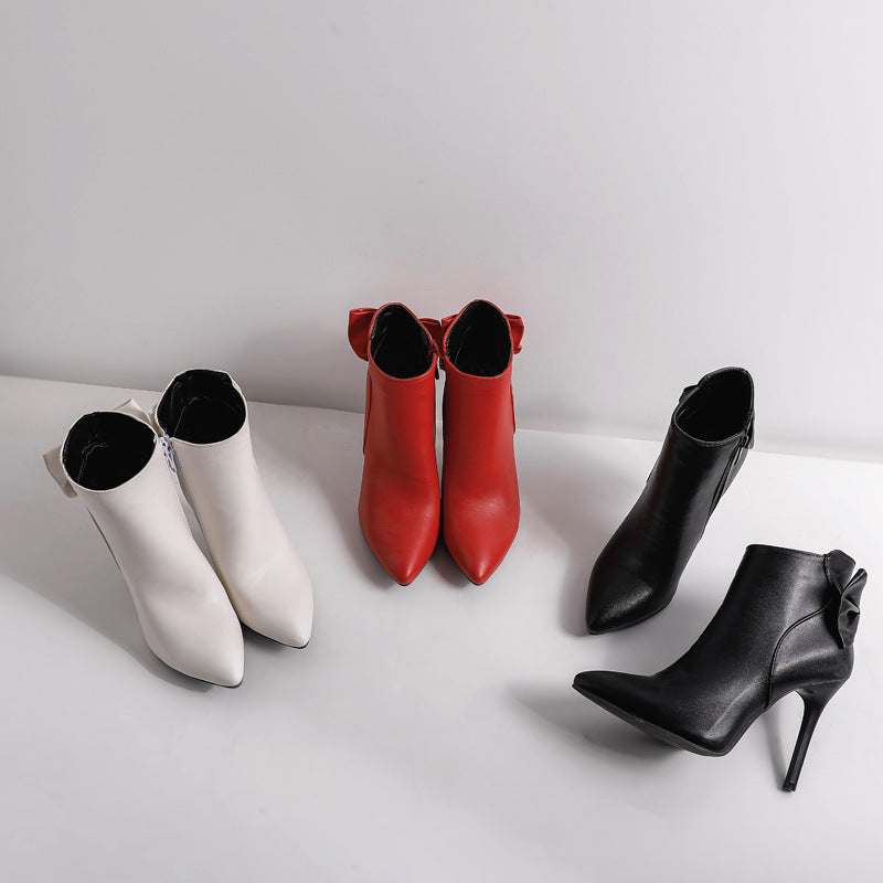 Three pairs of women's ankle boots in white, red, and black on a light gray background.