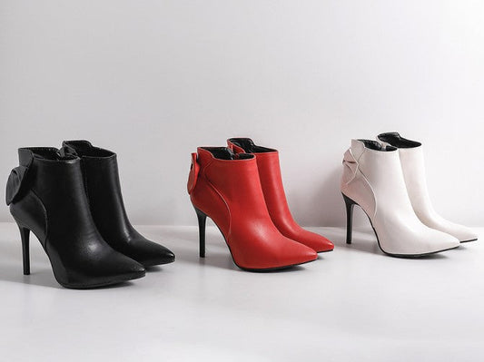 Black, red, and white high-heeled ankle boots on a light gray background