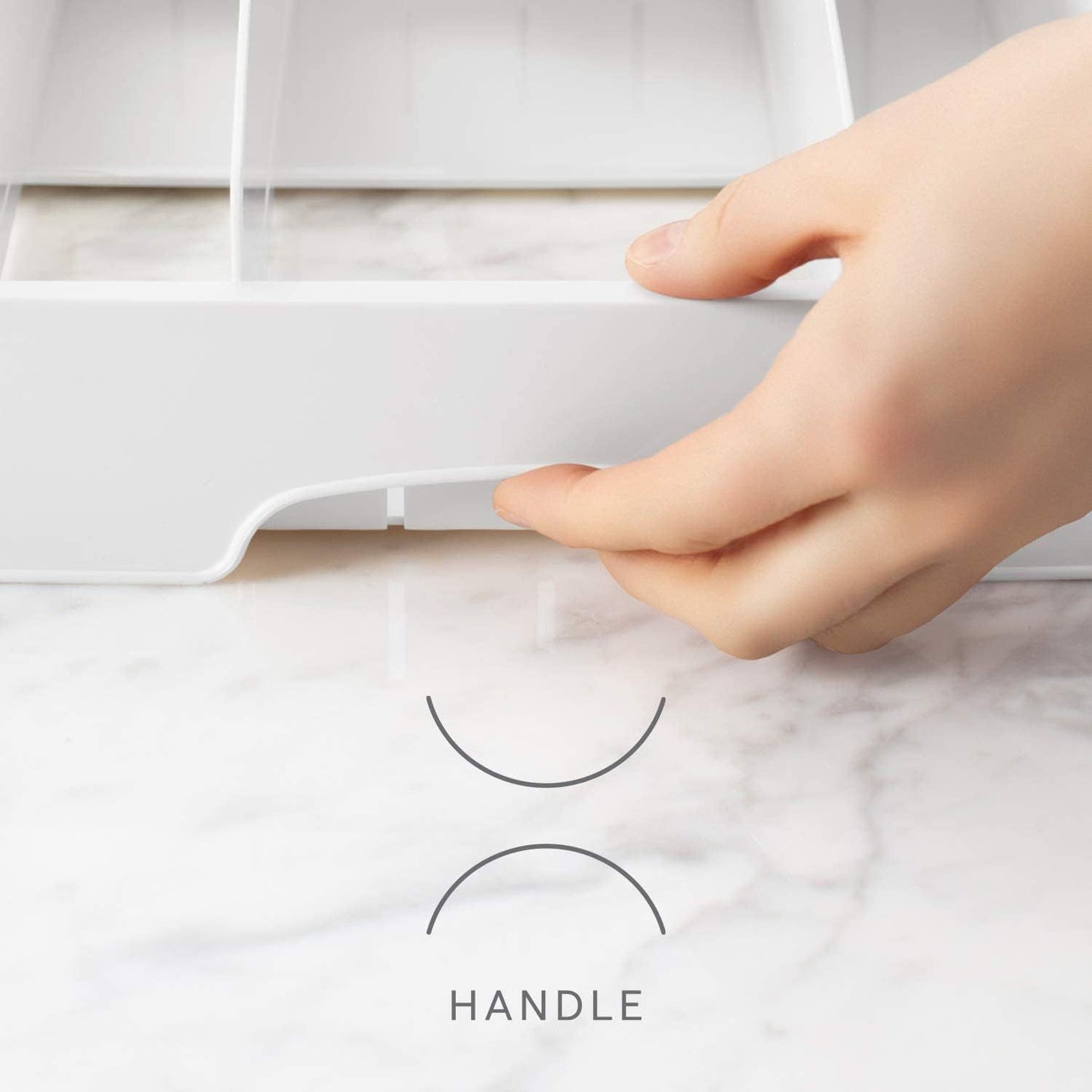 Hand holding a white product with a handle labeled on a marble surface