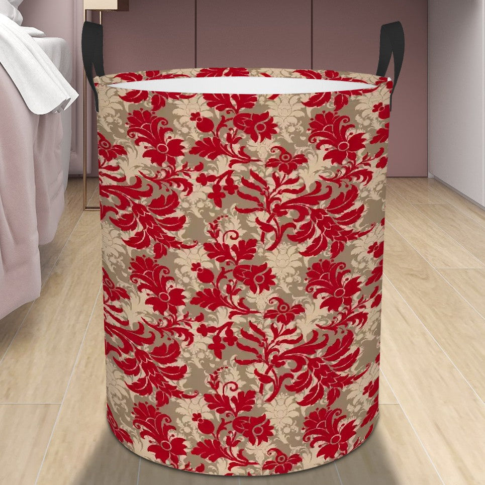 Decorative laundry basket with red floral pattern on a wooden floor next to a bed.