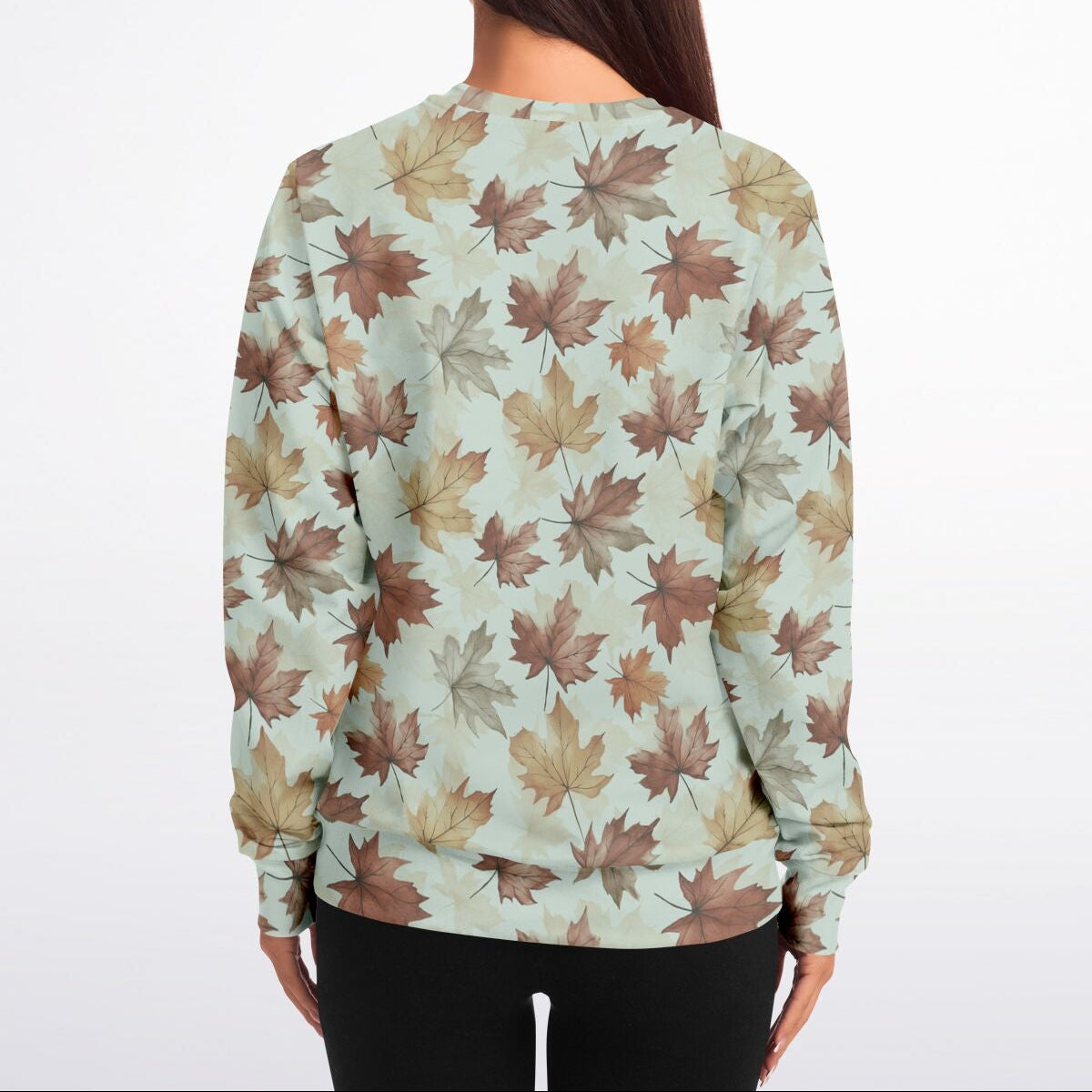 Person wearing a long-sleeve shirt with a leaf pattern on a plain background